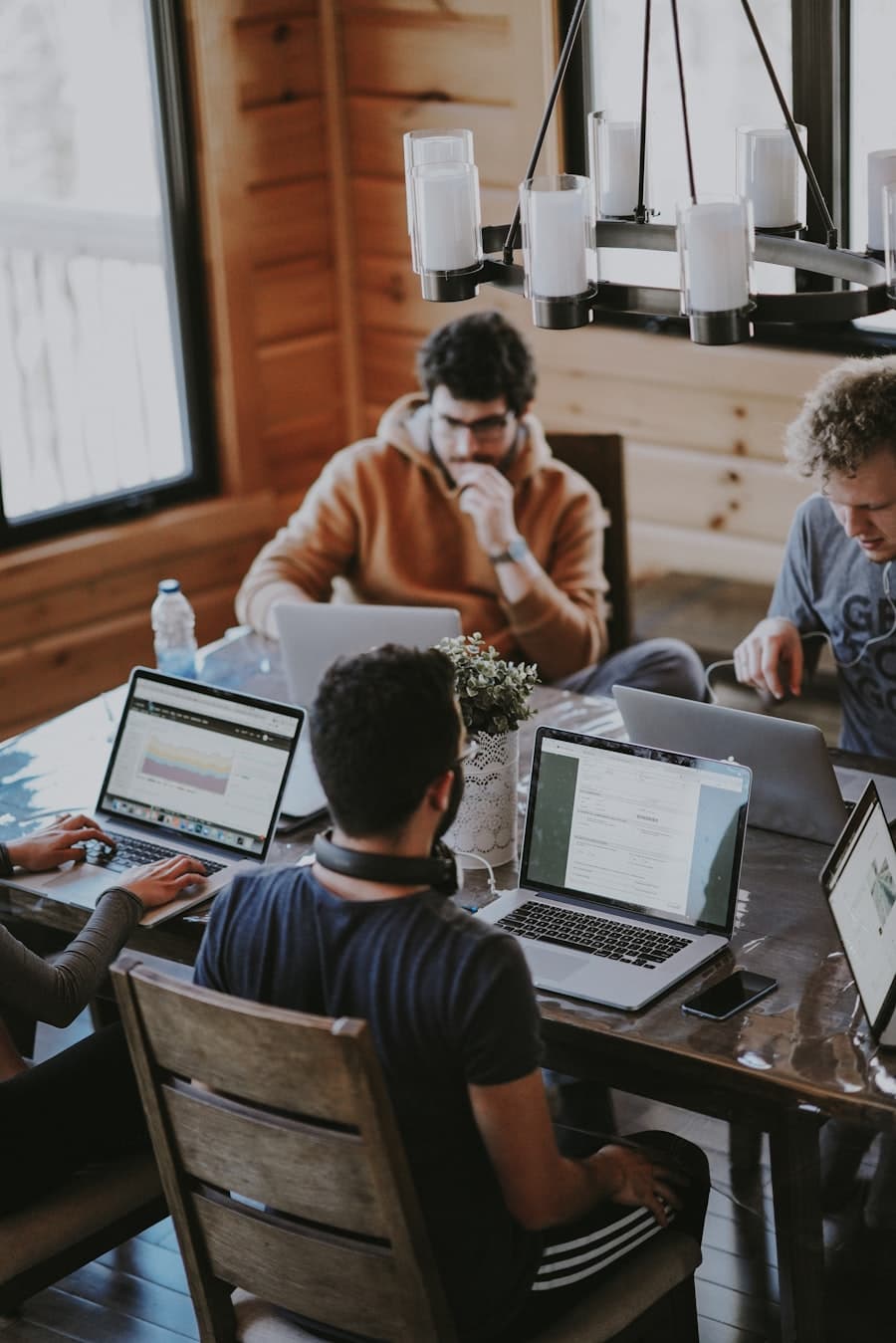 Team collaborating around a wooden table with laptops, warm interior